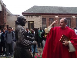  Fr. Luedtke blesses a statue of St. Ignatius at Loyola High School in Detroit.