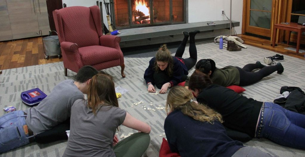 group of students laying on the floor playing scrabble
