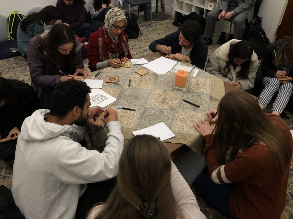 Students sitting around a table creating mosaic tiles