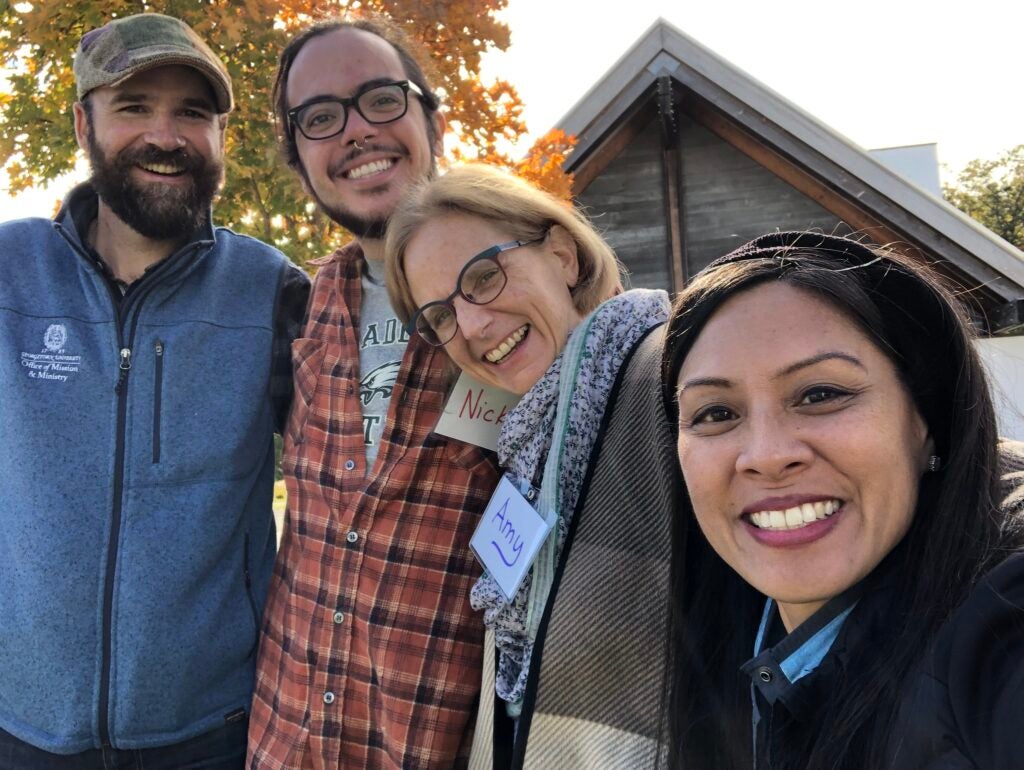 Four adults posing together outdoors in a fall setting