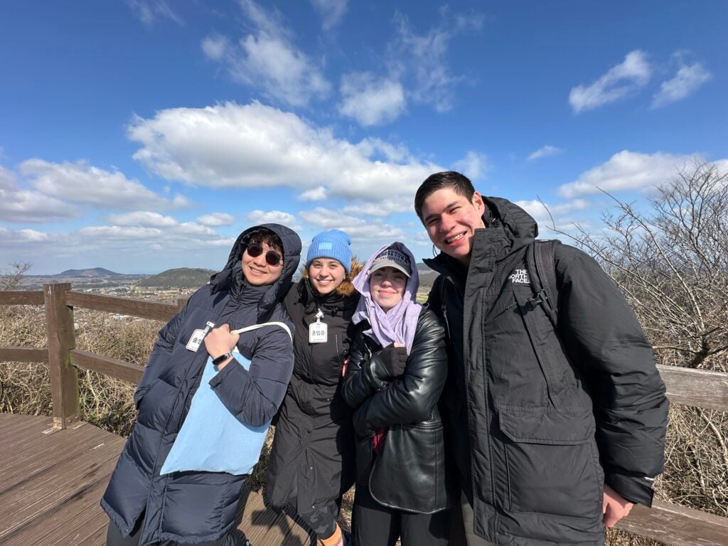 4 classmates pose for picture during hike on mountain. 