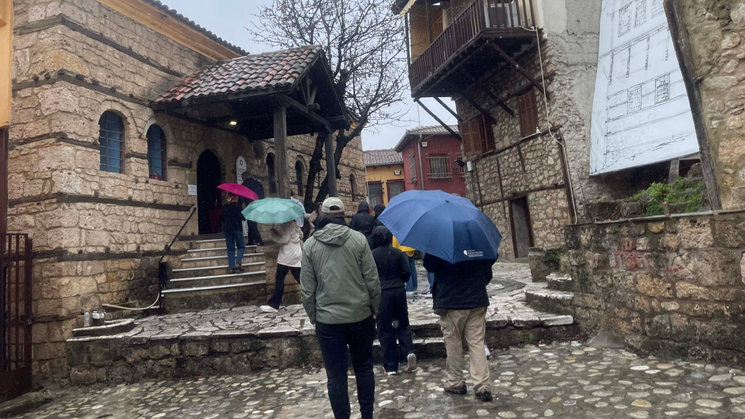 People, carrying umbrellas heading into a synagogue.