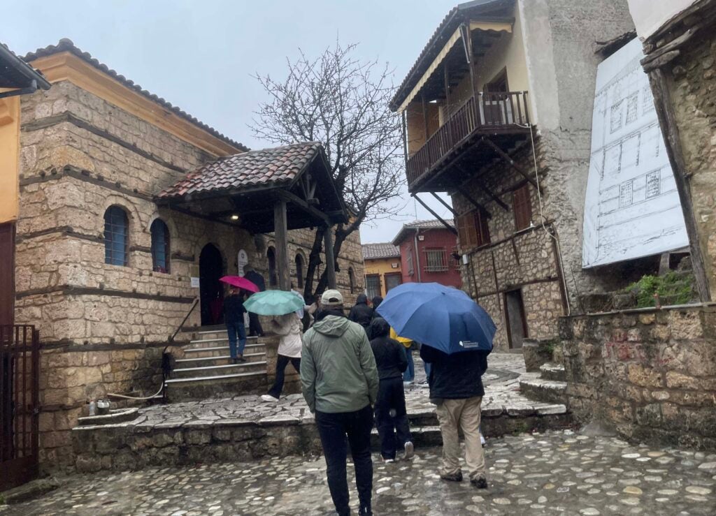 People, carrying umbrellas walking up the front steps to a synagogue. 