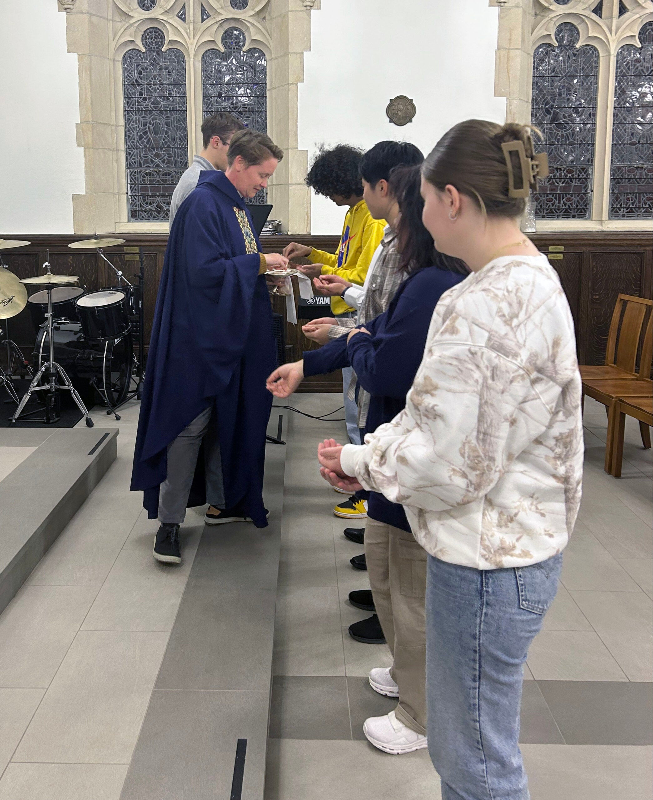 an Episcopal priest is distributing communion to students