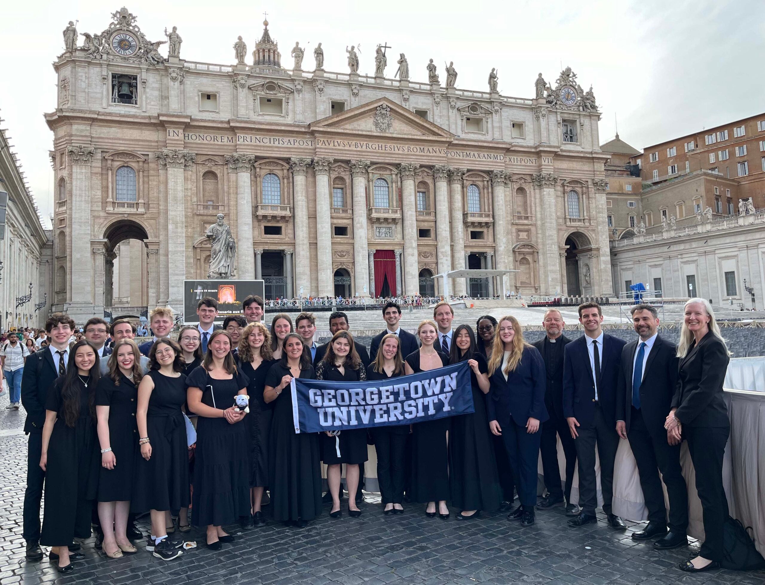 A group of students, and chaperones all dressed in black stand in St Peter's Square, Vatican City. 