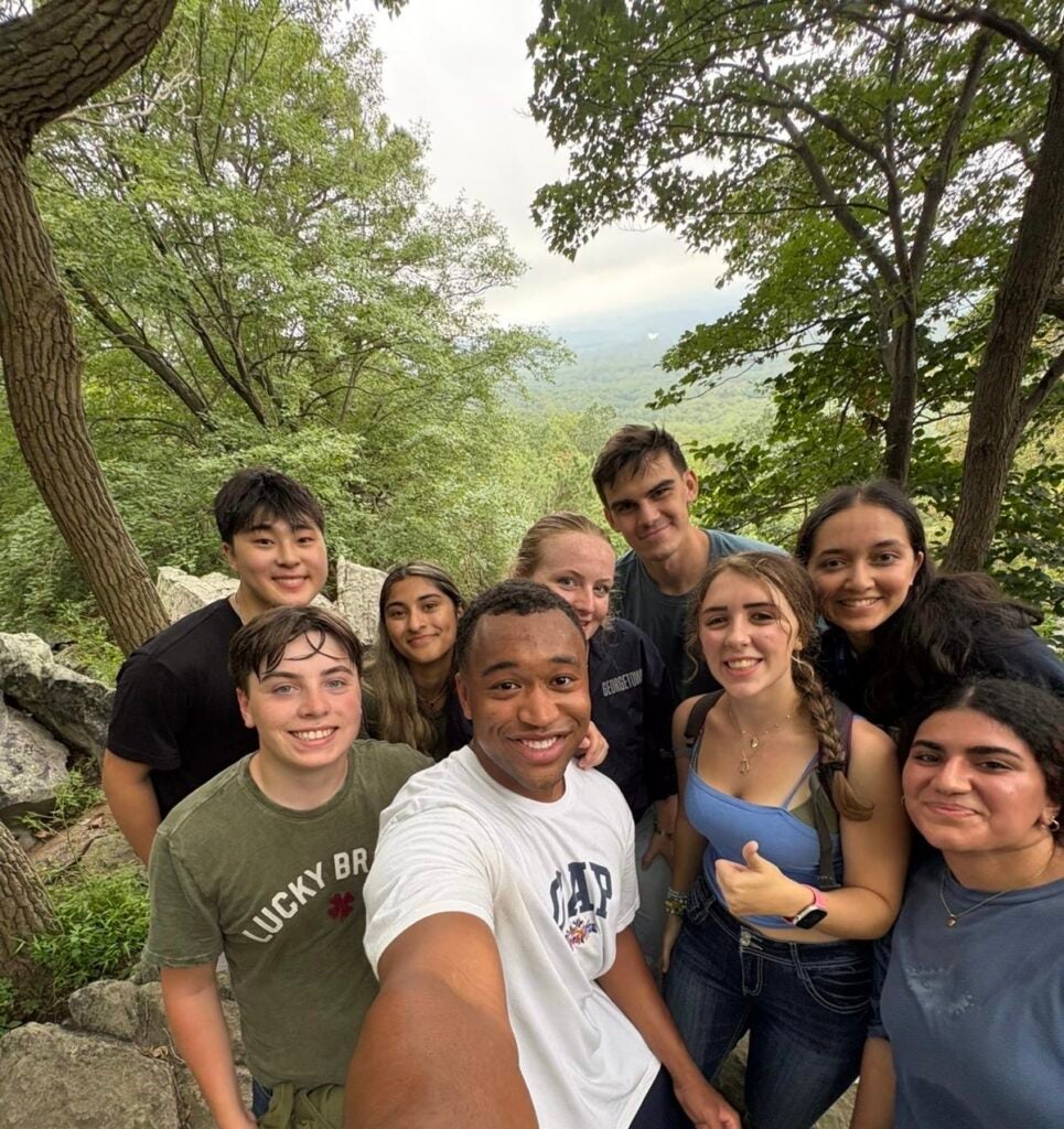 A group of students pause their hike in the woods to take a group selfie.