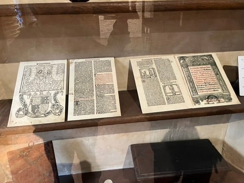 Two old printed books displayed in a glass museum case. 