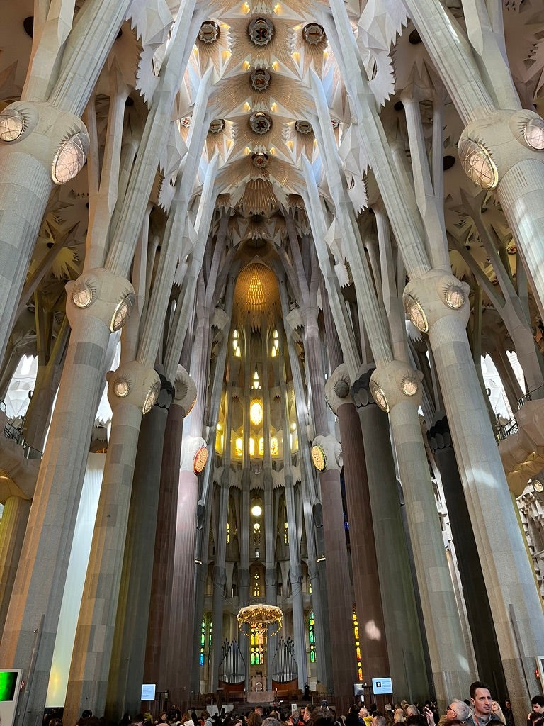 The interior of a basilica with tall white columns and geometric ceiling patterns. 