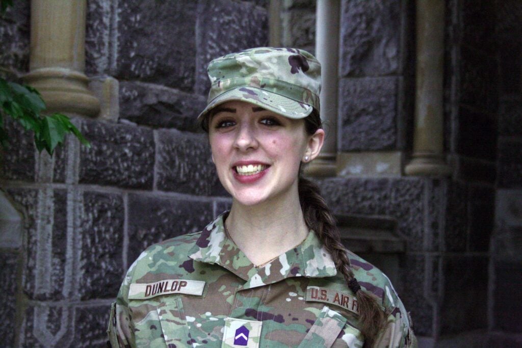 A head and shoulder shot of a young woman wearing a hat and shirt, army fatigues.