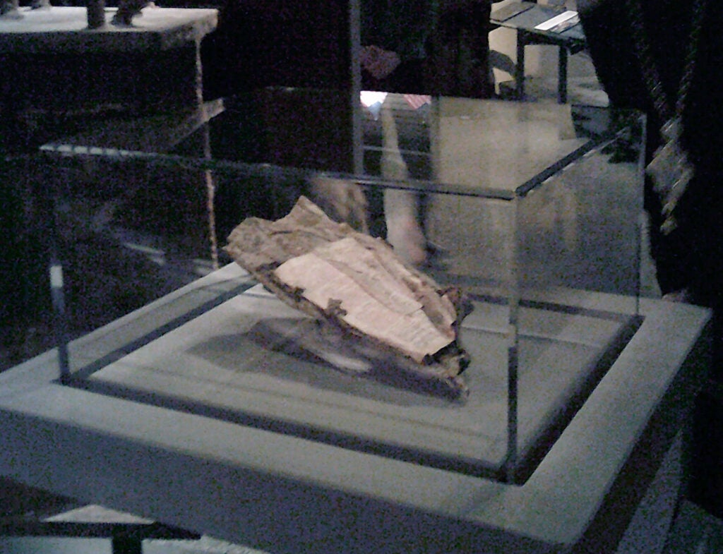 a slightly blurry, close up of a fragment of a Bible page in a vitrine.