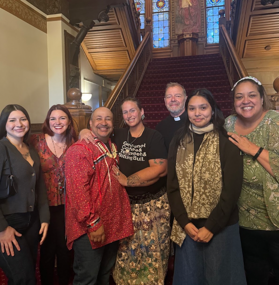 Seven people standing in front of a staircase smiling towards the camera