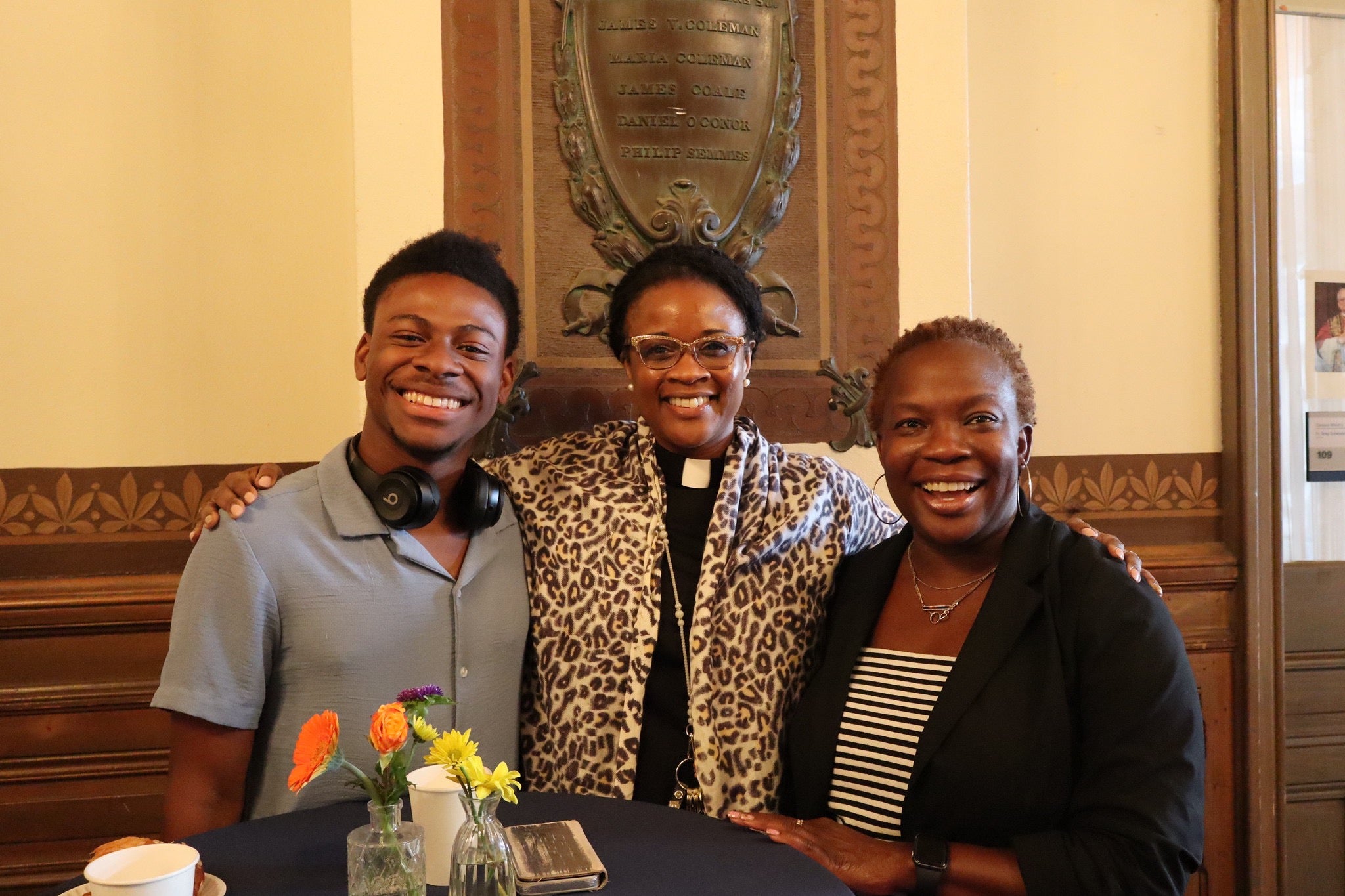 One man and two women standing in Healy Hall foyer behind a blue table